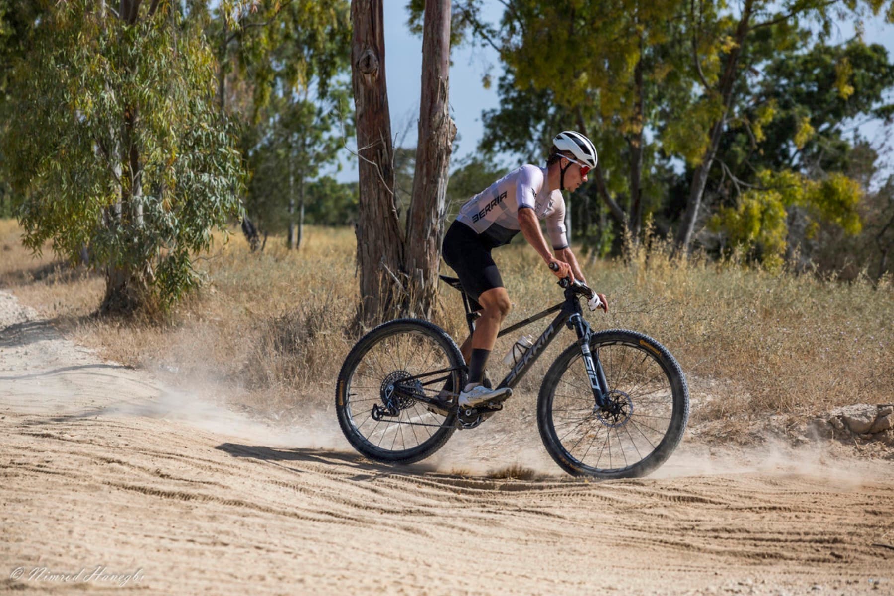 Tomer Caspi riding a technical rocky trail through a forest